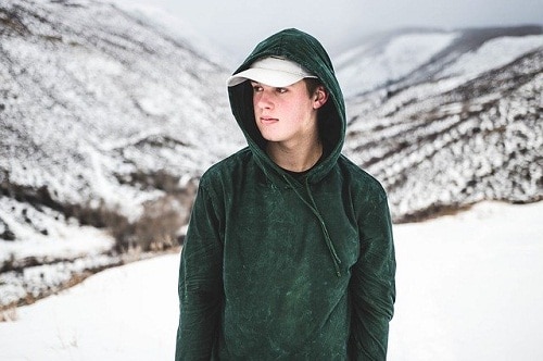 young man wearing wet hoody on a snowy mountain