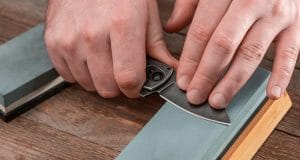 Man sharpening a pocket knife using a whetstone