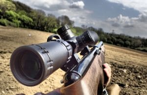 air rifle with scope held in an open field
