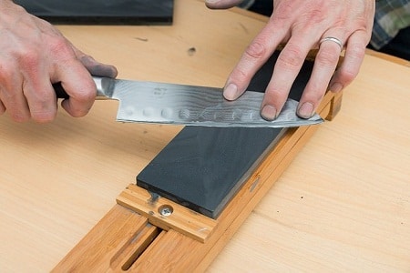 dirty hands sharpening a knife on whetstone