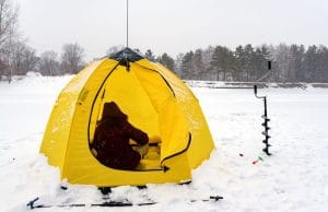 fisher in a yellow tent on snow