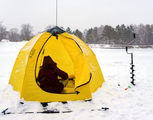 fisher in a yellow tent on snow