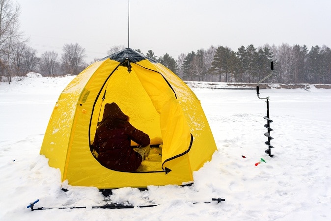 fisher in a yellow tent on snow 