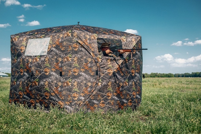 hunter aiming rifle from a ground blind