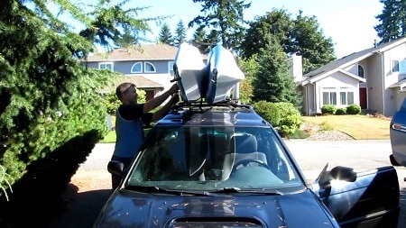 man securing kayaks on roof rack