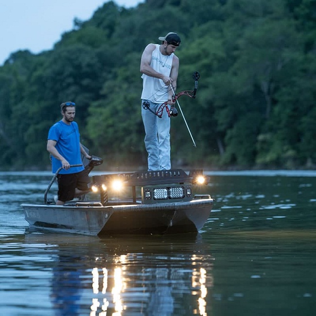 men bowfishing in the lake at dawn