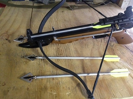 pistol crossbow at full draw on table with arrows