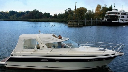 white motor boat with driver standing