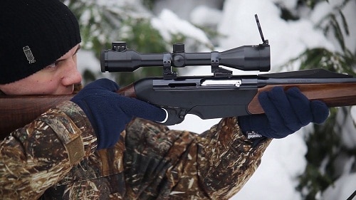 hunter aiming rifle with fixed magniifaction scope during winter