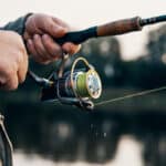 Man holding spincasting reel on a lake