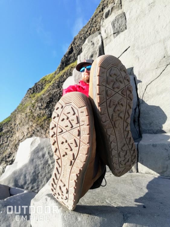 Sitting on rocks with legs crossed and bottom of Kodiak Skogan boots showing