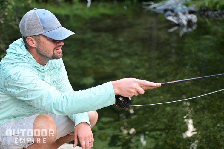 Man crouched down fly fishing