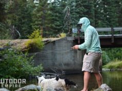 Man fly fishing in river wearing with dog by side