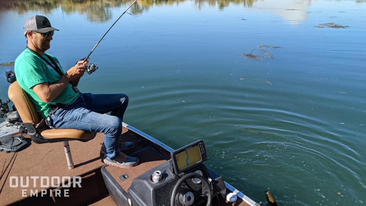 Man fishing for bass from a boat while sitting