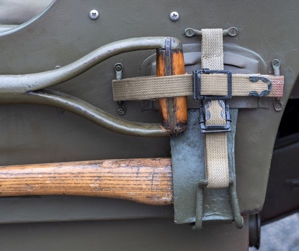 Axe and shovel securely strapped on the side of a vehicle