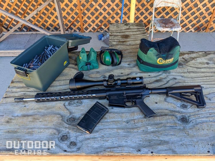 Ar-10 laying on table next to range gear and ammo