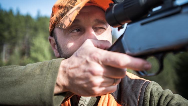 hunter in orange hat aiming rifle