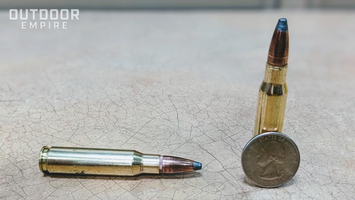 Two .308 cartridges on a table with a quarter next to them for scale.