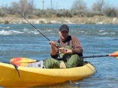 Man in river fishing in a kayak