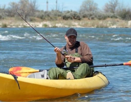 Man in river fishing in a kayak
