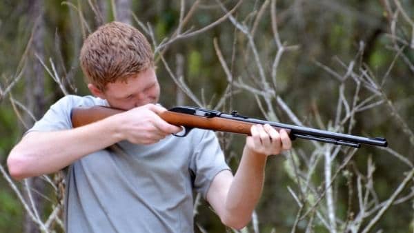 Man aiming rifle outdoors
