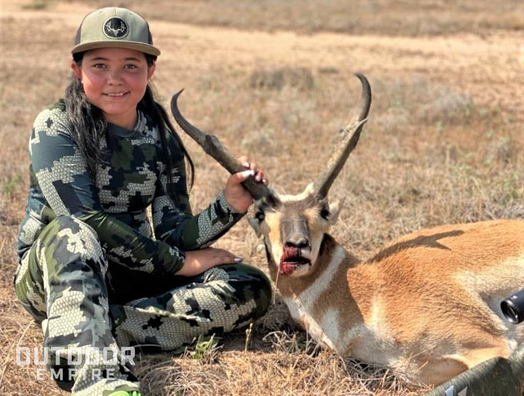 Kid sitting and holding horn of recently shot pronghorn antelope