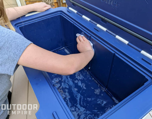 Woman cleaning a blue cooler