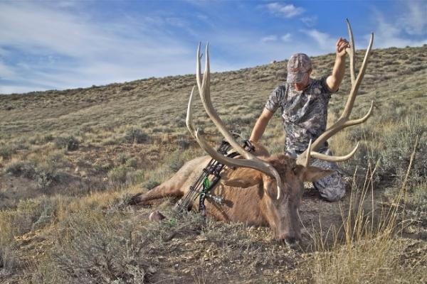 hunter with trophy elk in a grassland