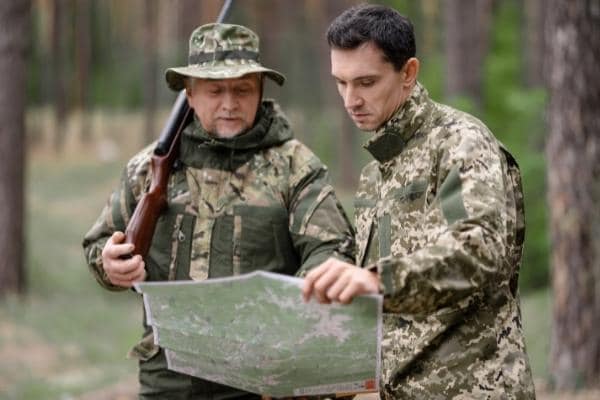 Hunters studying map in the forest