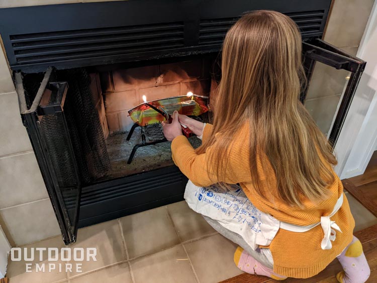 girl lighting a firelog in fireplace