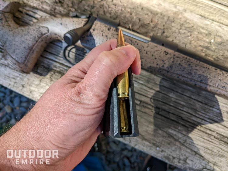 Mans hand loading 7. 62 rounds into a magazine