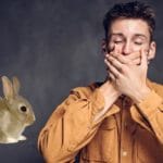 Rabbit beside a man covering his mouth