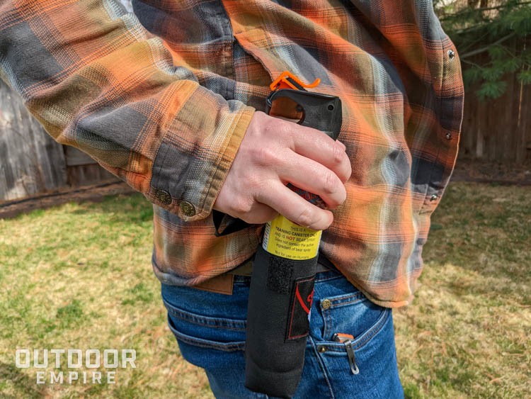 Man removing can of bear spray from belt holster