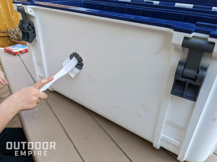Scrubbing outside of a cooler with a brush
