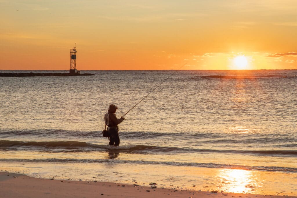 Angler surf fishing during sunrise