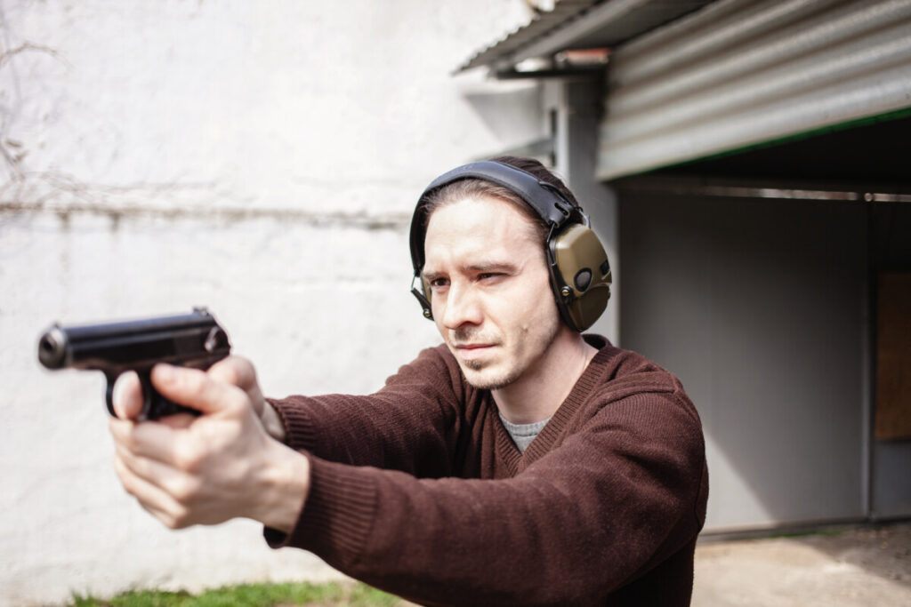 man wearing earmuff aiming gun 