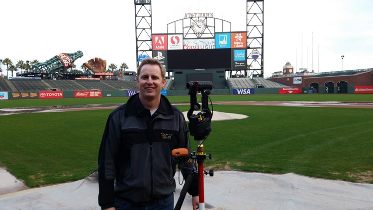 man standing in San Francisco Giants stadium with laser rangefinder equipment
