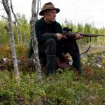 Old hunter with rifle sitting
