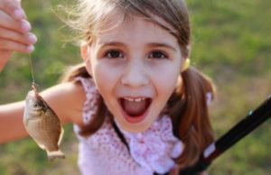 young girl holding hooked fish