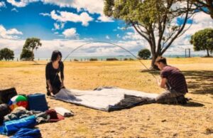 couple setting up tent on ground sheet