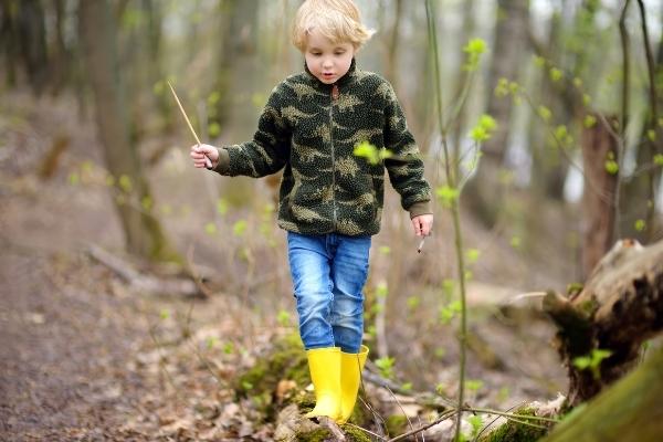 Kid in rain boots walking in the woods