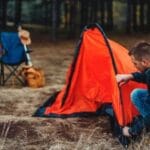 Man setting up tent in campsite