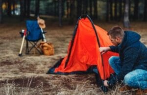 man setting up tent in campsite
