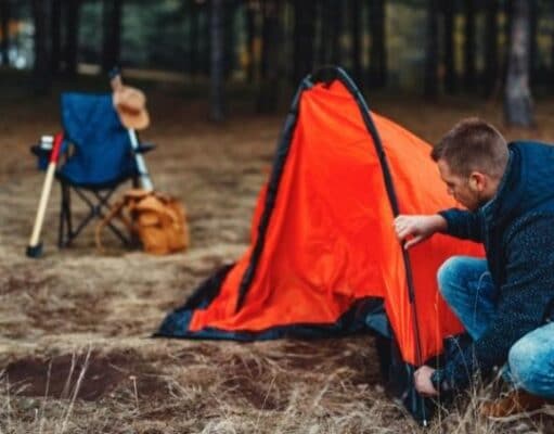 man setting up tent in campsite