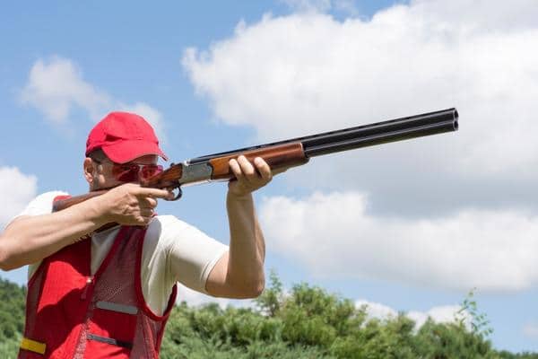 man aiming sporting shotgun in the field