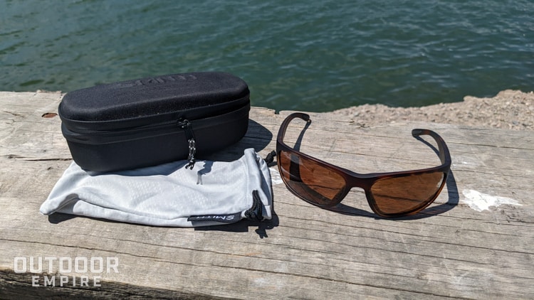 Sunglasses next to hard case and soft case on bench