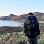 Hiker carrying gregory focal overlooking reservoir