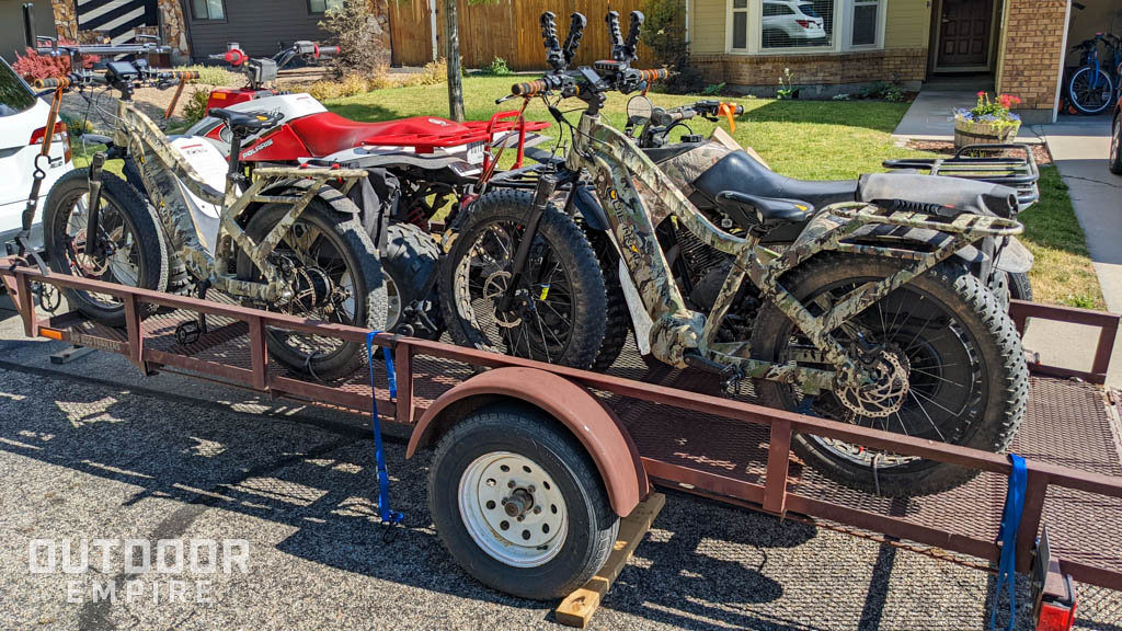 Two electric bikes on a trailer with ATVs