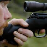 Man looking through a rifle scope