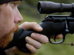 man looking through a rifle scope